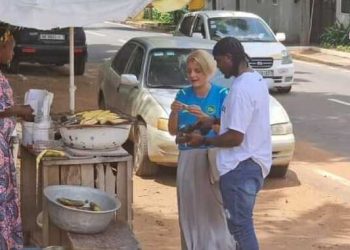 Black Stars goalkeeper Lawrence Ati-Zigi and Swiss Ambassador to Ghana seen getting a roasted plantain on the streets of Accra